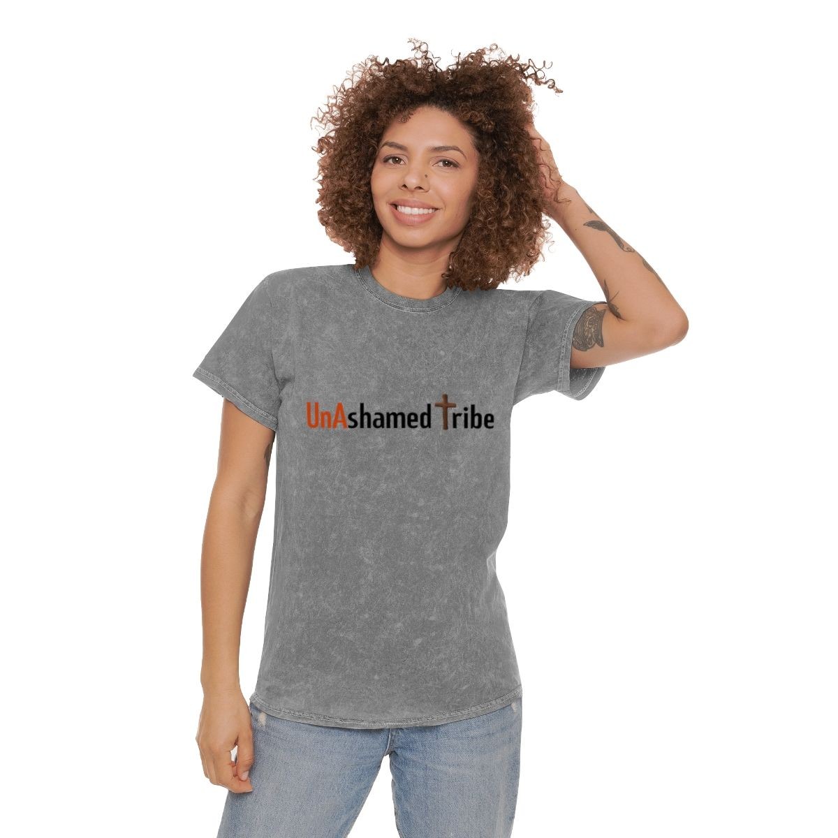 Smiling person wearing a gray shirt with 'UnAshamed Tribe' and a cross design.